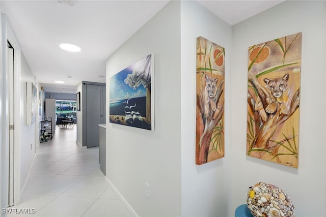 corridor featuring baseboards and light tile patterned floors