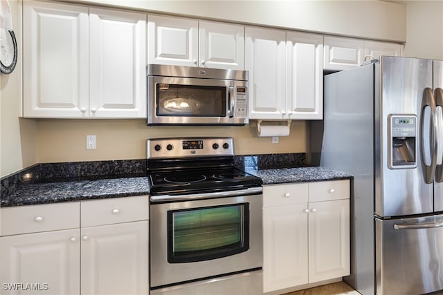 kitchen with dark stone countertops, white cabinets, and appliances with stainless steel finishes