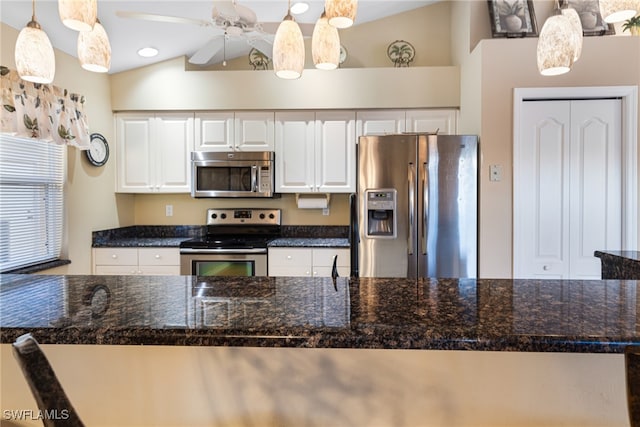 kitchen with white cabinets, appliances with stainless steel finishes, vaulted ceiling, and pendant lighting