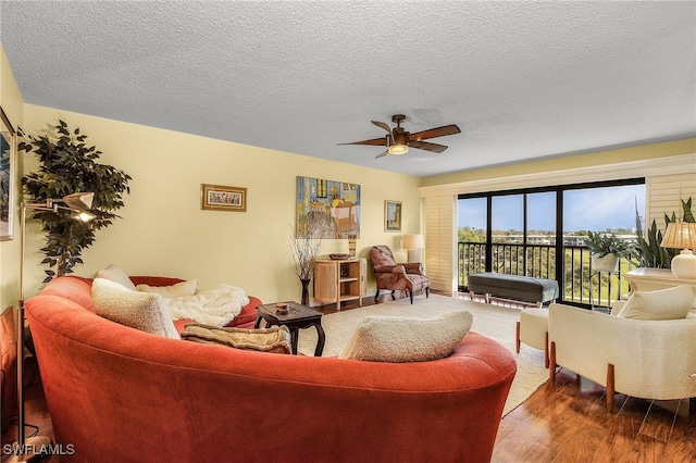 living room with ceiling fan, a textured ceiling, and hardwood / wood-style flooring