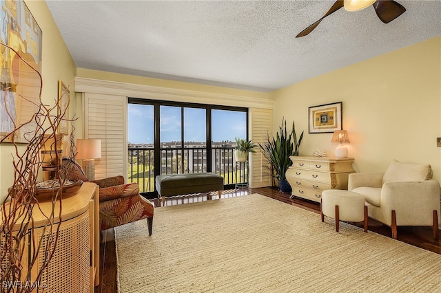 sitting room with wood-type flooring, a textured ceiling, and ceiling fan