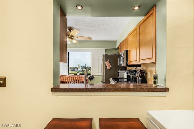 kitchen with decorative backsplash, ceiling fan, a textured ceiling, and appliances with stainless steel finishes