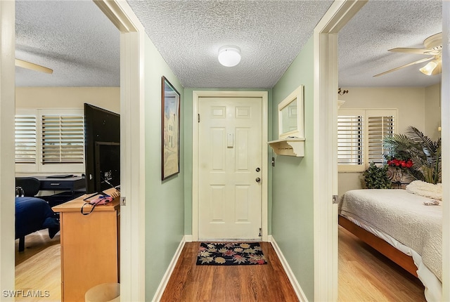 doorway featuring ceiling fan, a textured ceiling, and light hardwood / wood-style flooring