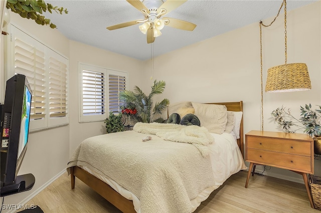 bedroom with ceiling fan, light hardwood / wood-style floors, and a textured ceiling