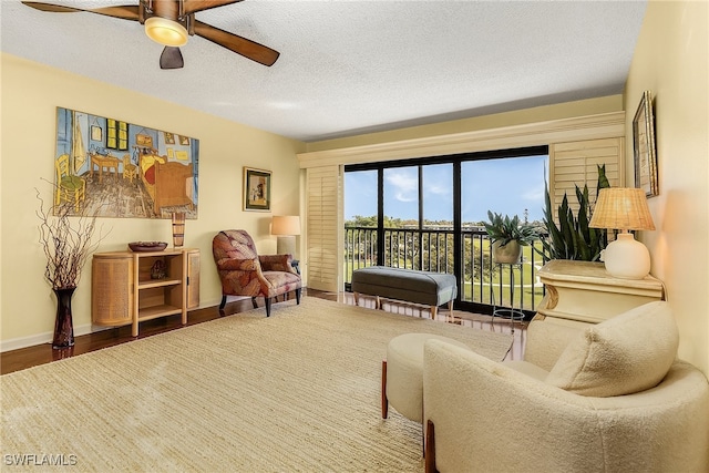 sitting room featuring ceiling fan, wood-type flooring, and a textured ceiling