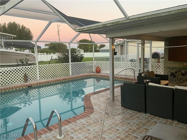 pool at dusk featuring glass enclosure, a patio area, and outdoor lounge area