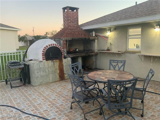 patio terrace at dusk featuring a fireplace