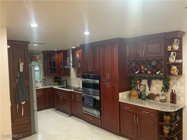 kitchen with light tile patterned floors, appliances with stainless steel finishes, tasteful backsplash, light stone countertops, and wall chimney range hood