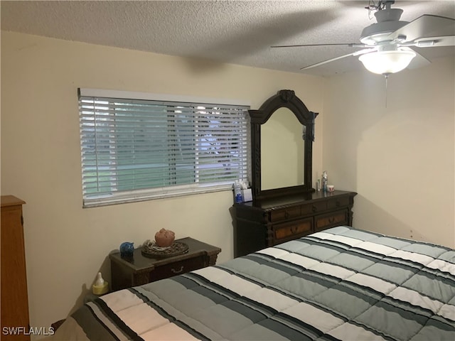 bedroom with ceiling fan and a textured ceiling