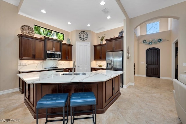 7399 Acorn Way, Naples, FL 34119 - kitchen with a sink, stainless steel appliances, arched walkways, a large island, and light stone counters