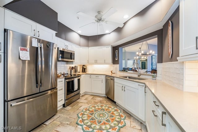 kitchen with sink, tasteful backsplash, white cabinets, ceiling fan with notable chandelier, and appliances with stainless steel finishes