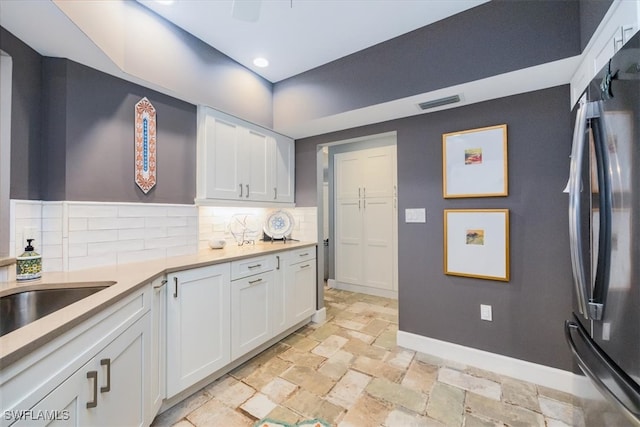 kitchen with tasteful backsplash, stainless steel refrigerator, and white cabinets