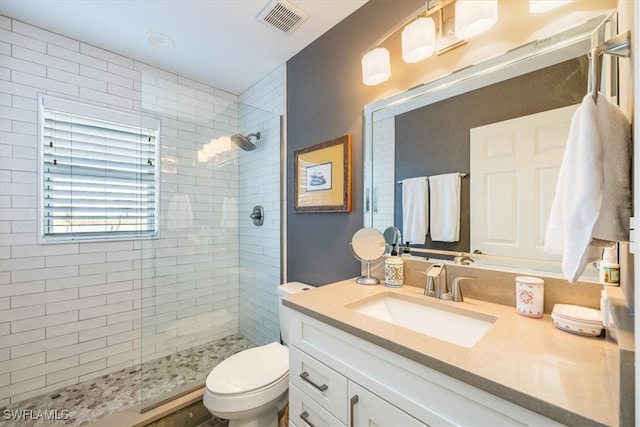 bathroom featuring a tile shower, vanity, and toilet