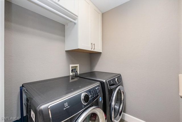 laundry area with separate washer and dryer and cabinets