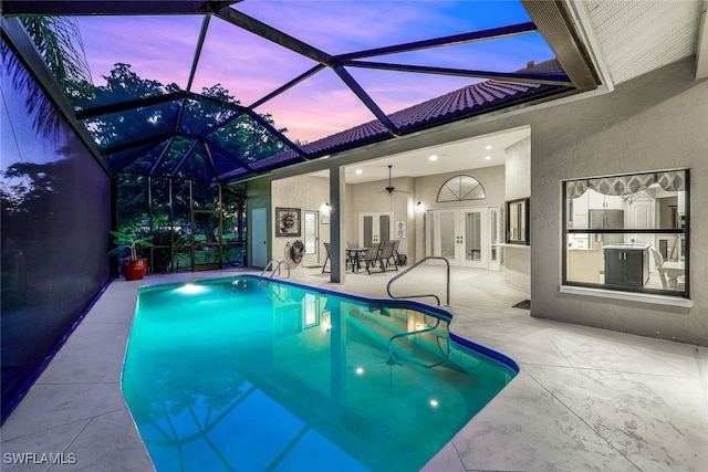 pool at dusk with french doors, a patio, glass enclosure, and ceiling fan