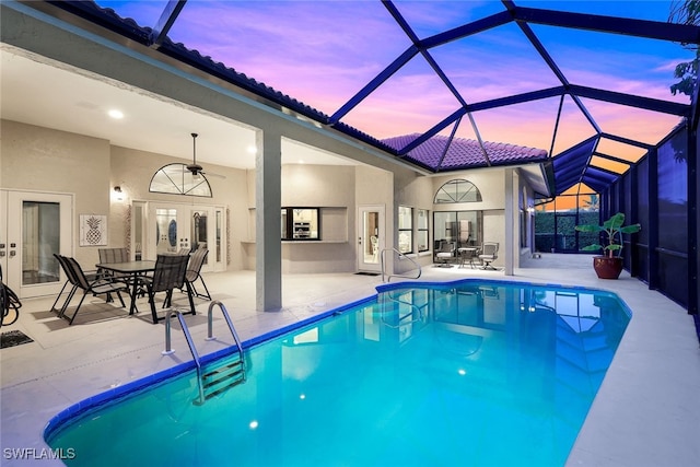 pool at dusk featuring french doors, a patio, glass enclosure, and ceiling fan