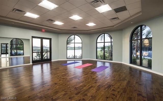 exercise room with french doors, a paneled ceiling, and hardwood / wood-style flooring