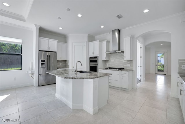 kitchen featuring appliances with stainless steel finishes, a center island with sink, wall chimney exhaust hood, and sink