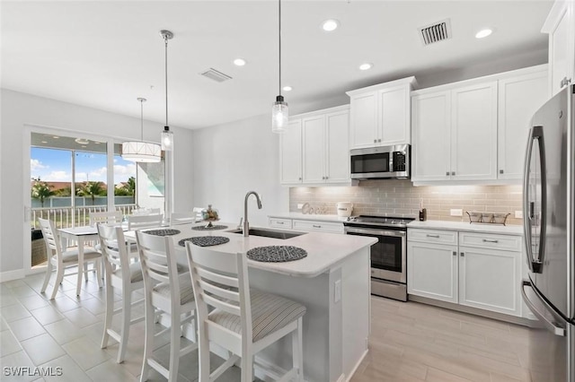 kitchen featuring sink, hanging light fixtures, white cabinets, and stainless steel appliances