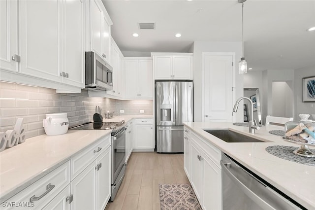 kitchen with white cabinetry, sink, hanging light fixtures, tasteful backsplash, and appliances with stainless steel finishes