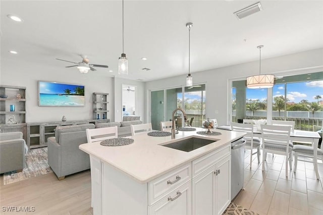 kitchen featuring a center island with sink, white cabinetry, sink, and pendant lighting