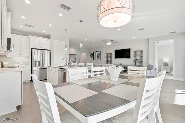 dining room featuring ceiling fan, sink, and light hardwood / wood-style flooring