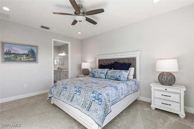 bedroom with connected bathroom, light colored carpet, and ceiling fan