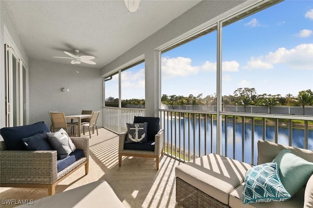 sunroom / solarium featuring ceiling fan and a water view