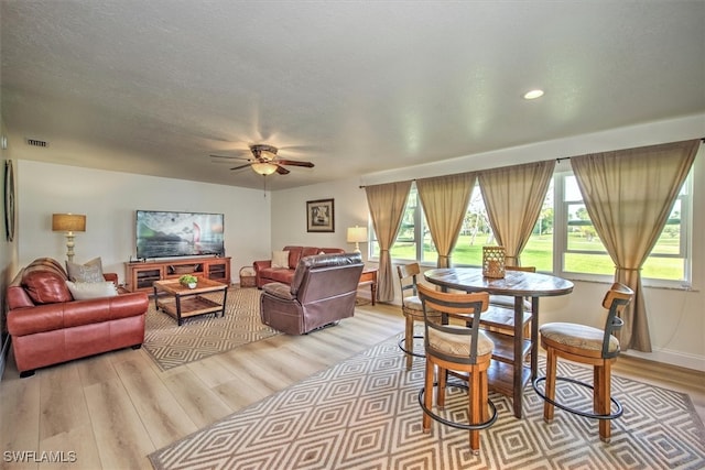 dining room with ceiling fan, light wood-type flooring, and a textured ceiling