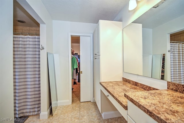 bathroom with a textured ceiling, vanity, tile patterned floors, and a shower with curtain