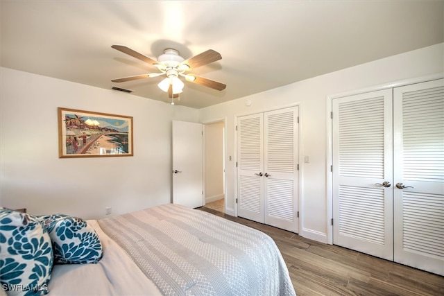 bedroom featuring multiple closets, ceiling fan, and light wood-type flooring