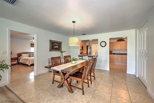 dining space with ceiling fan, light tile patterned floors, and a textured ceiling