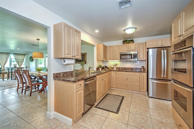 kitchen with pendant lighting, light brown cabinets, sink, and stainless steel appliances