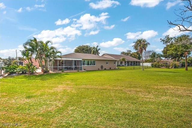 1656 Saint Clair Ave E, North Fort Myers, FL 33903 - rear view of house featuring a sunroom, a lawn, and stucco siding