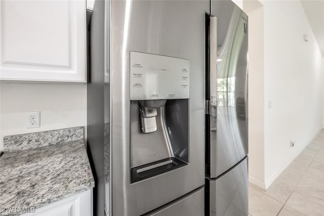 details featuring white cabinets, light stone countertops, and stainless steel refrigerator with ice dispenser