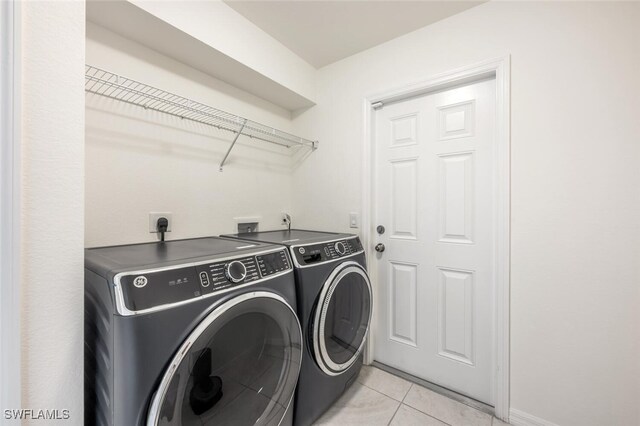 clothes washing area featuring washing machine and clothes dryer and light tile patterned floors