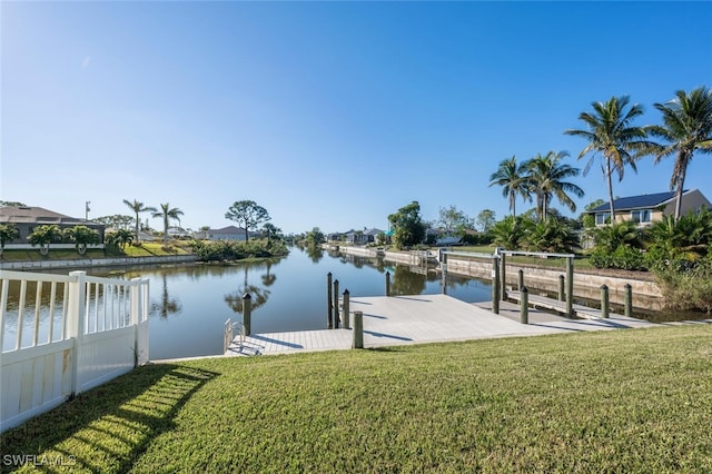 view of dock with a lawn and a water view