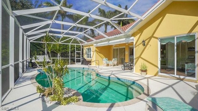 view of swimming pool featuring glass enclosure and a patio