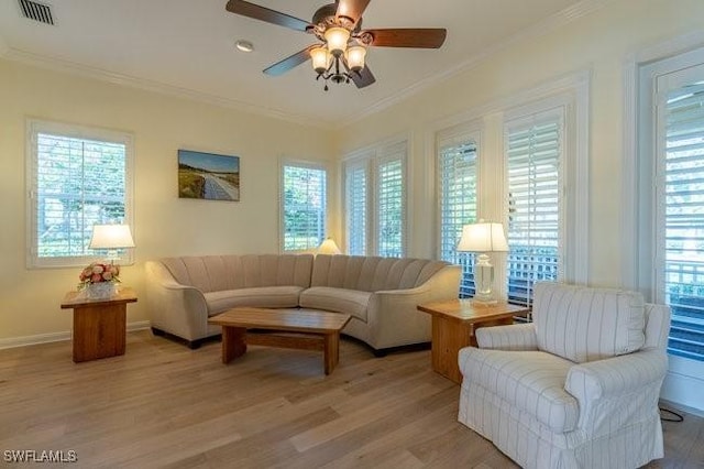 living room featuring ceiling fan, light wood-type flooring, ornamental molding, and a wealth of natural light