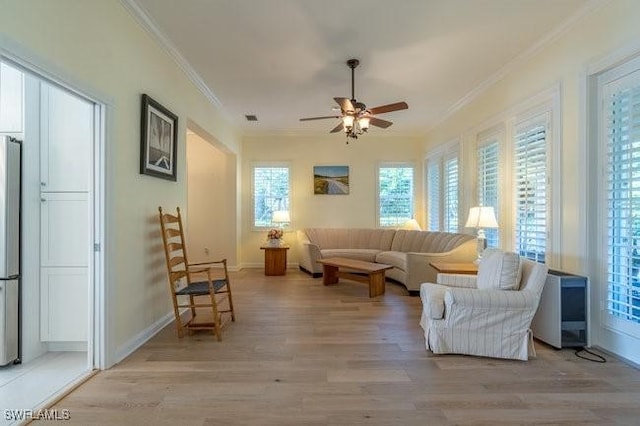 living room featuring ceiling fan, plenty of natural light, ornamental molding, and light hardwood / wood-style flooring