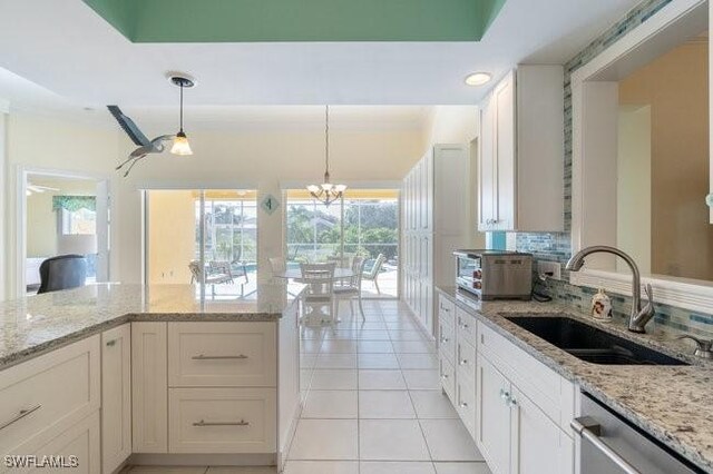 kitchen with white cabinets, plenty of natural light, light stone counters, and sink