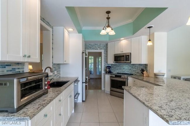 kitchen with light stone countertops, white cabinetry, sink, hanging light fixtures, and appliances with stainless steel finishes