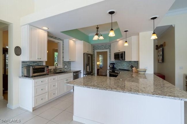 kitchen with kitchen peninsula, hanging light fixtures, decorative backsplash, white cabinetry, and stainless steel appliances