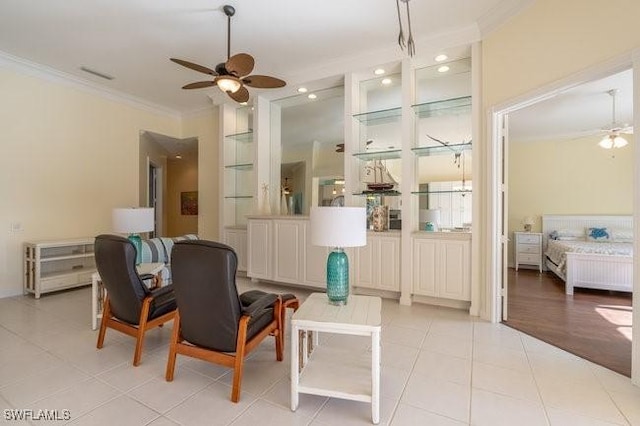 living area with light tile patterned floors, ceiling fan, and crown molding