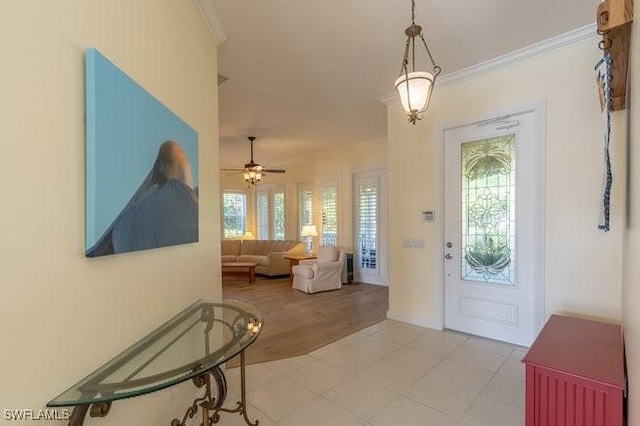 foyer featuring crown molding, ceiling fan, and light wood-type flooring