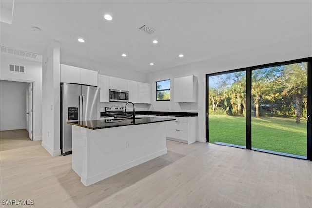 kitchen featuring white cabinetry, a kitchen island with sink, light hardwood / wood-style floors, and appliances with stainless steel finishes