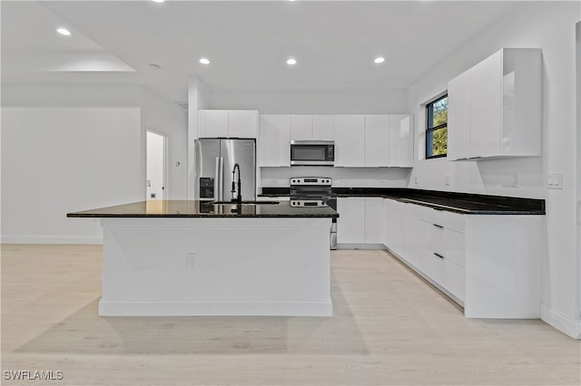 kitchen featuring a kitchen island with sink, white cabinets, sink, light hardwood / wood-style flooring, and stainless steel appliances