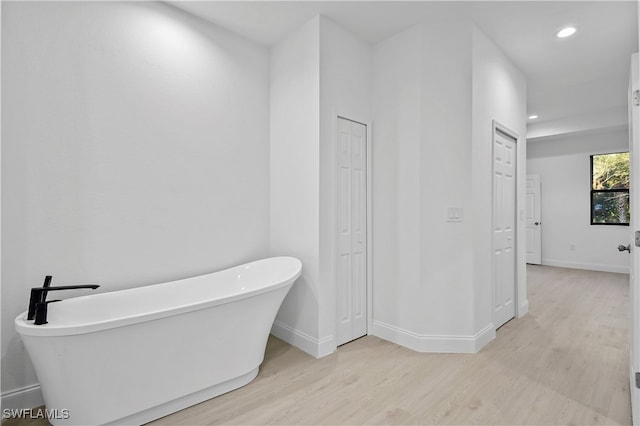 bathroom with hardwood / wood-style floors and a bath