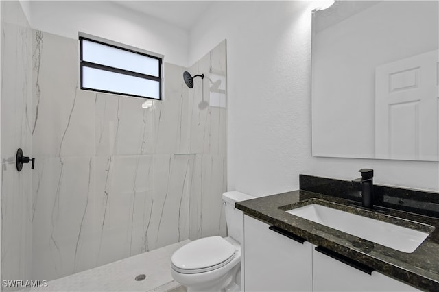 bathroom with a tile shower, vanity, and toilet