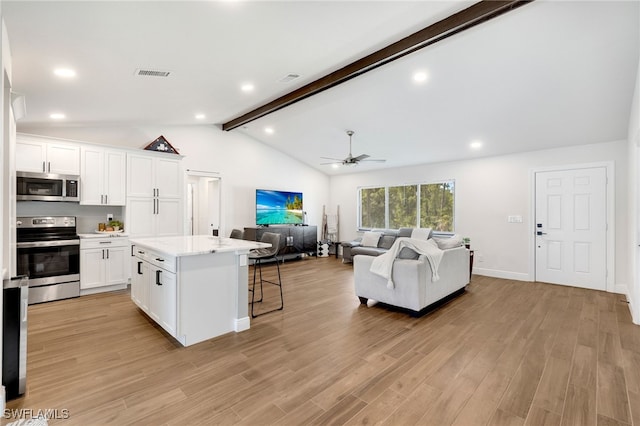 kitchen featuring stainless steel appliances, a kitchen island, lofted ceiling with beams, light hardwood / wood-style flooring, and white cabinetry